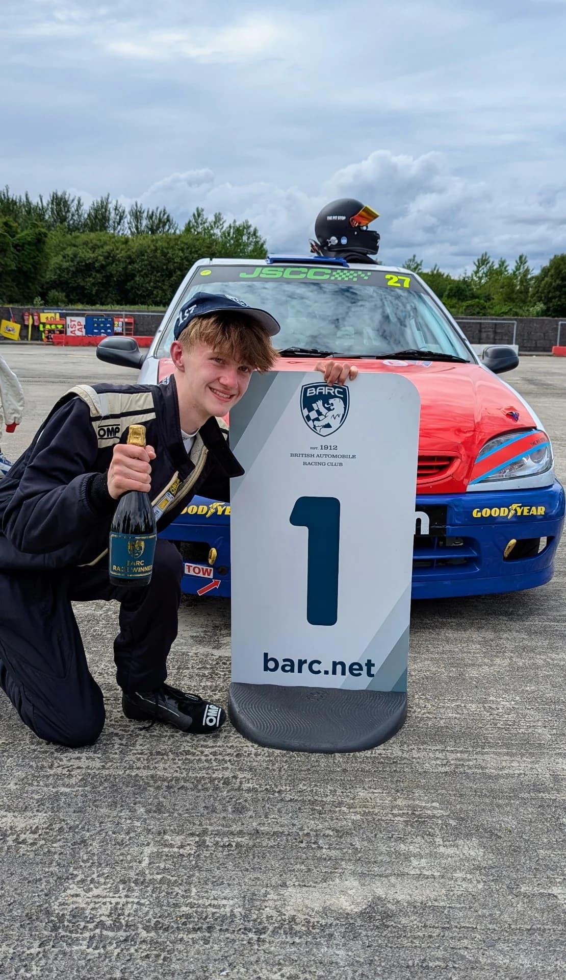Matthew Swatton crouches next to the winners sign after race one at Pembrey circuit